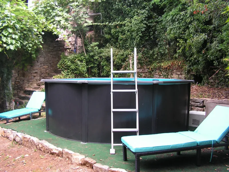 Piscine hors-sol entourée de transats dans la cour du mas