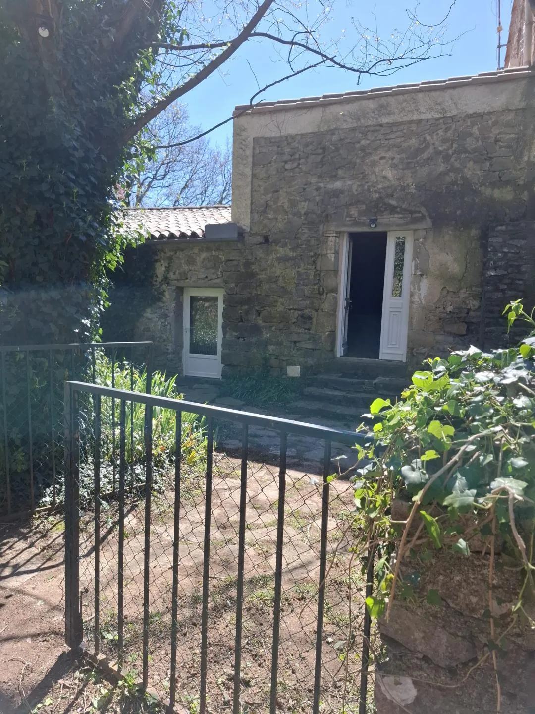 Gîte de groupe Mas de Gréfeuille à Monoblet — Façade en pierre du Mas de Gréfeuille avec son portail d'entrée dans un écrin de verdure, capacité 12 personnes