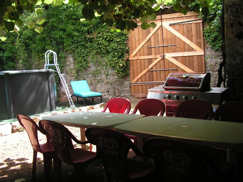 Terrasse extérieure avec grande table, chaises et coin barbecue