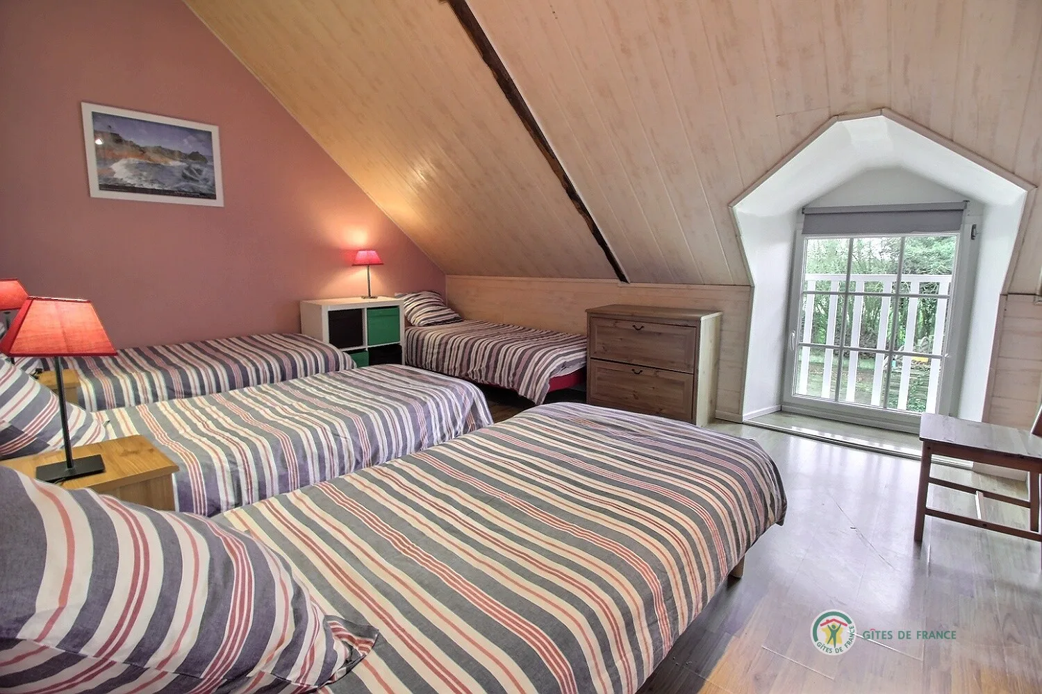 Chambre aux tons roses avec deux lits simples et parquet