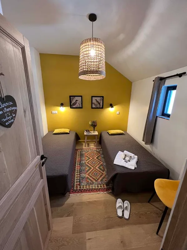 Chambre Hourgade avec mur jaune moutarde et lits jumeaux
