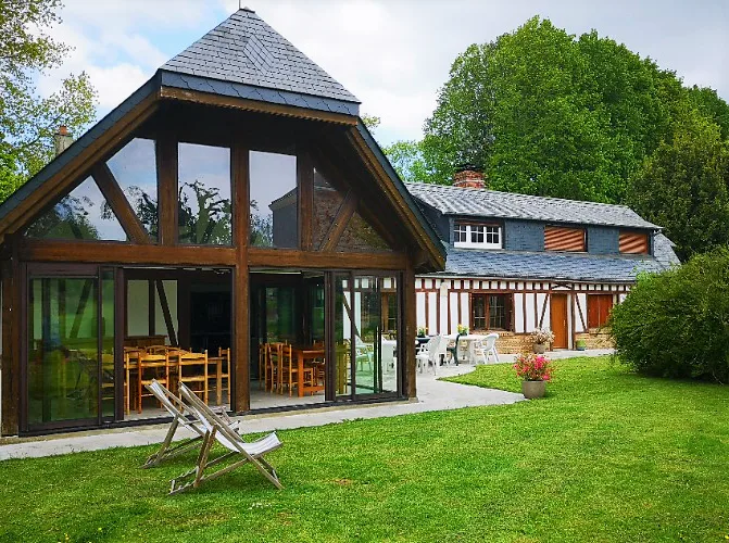 Façade à colombages normande avec jardin arboré et transats