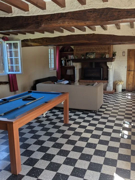 Salon avec billard et cheminée sous poutres apparentes