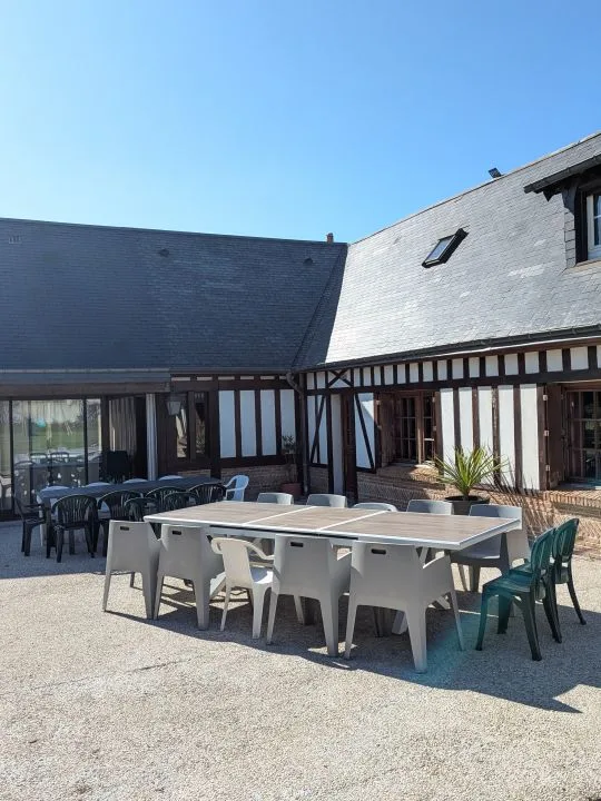 Terrasse extérieure avec grande table pour repas de groupe devant la maison à colombages