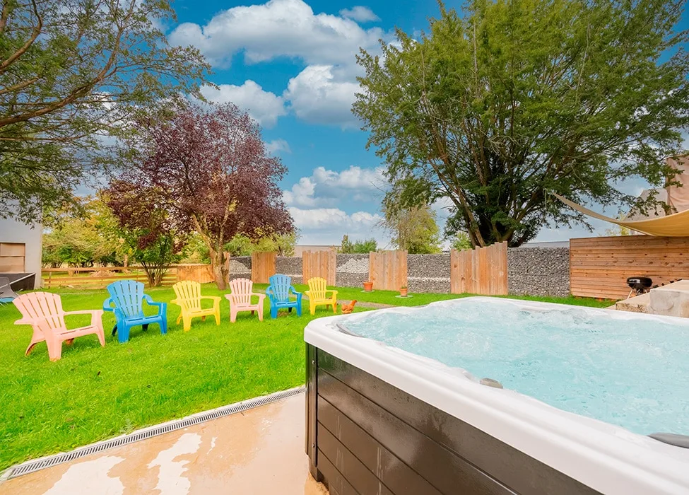 Spa extérieur chauffé entouré de chaises colorées sur la terrasse