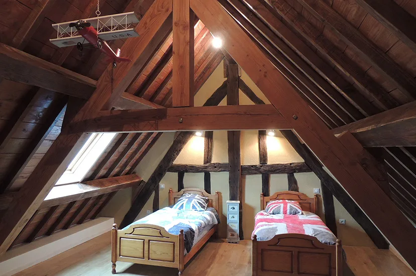 Chambre mansardée sous charpente apparente avec deux lits simples