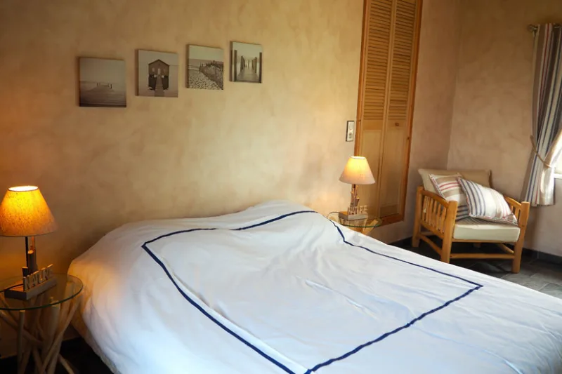 Chambre chaleureuse avec lit double, lampe de chevet et fauteuil
