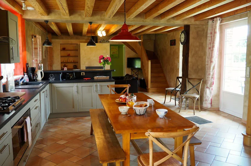 Cuisine équipée avec grande table en bois pour les repas de groupe sous charpente