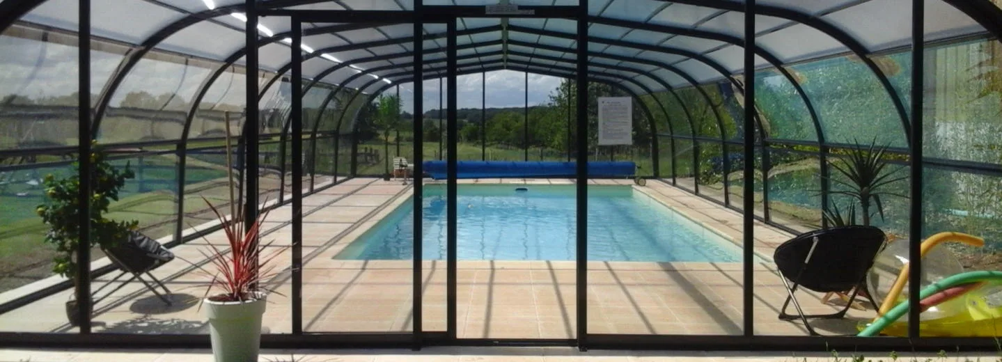 Piscine couverte et chauffée avec véranda vitrée et transats