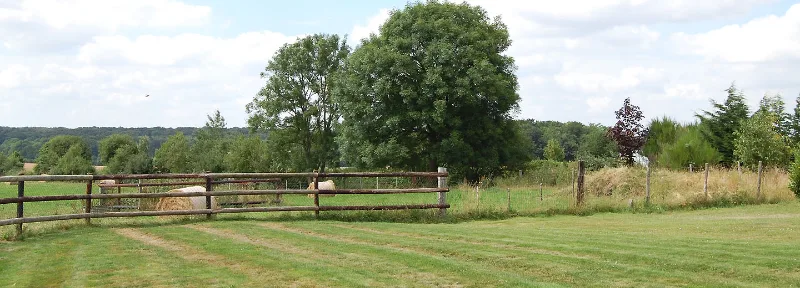 Longère en pierre normande avec toiture et clôture en bois, façade ensoleillée