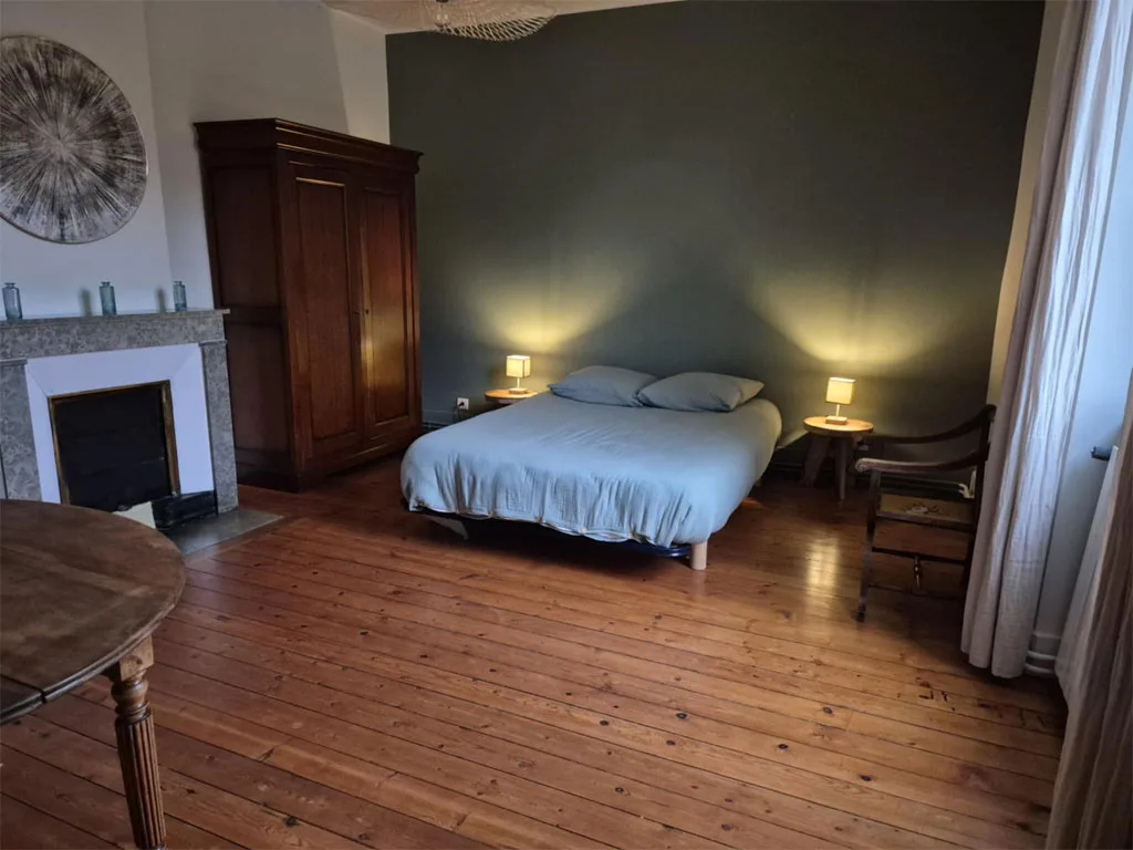 Chambre élégante avec cheminée en pierre et lit double face à la fenêtre