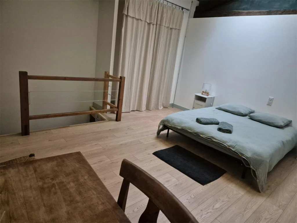 Chambre mansardée avec lit double sous velux et poutres apparentes