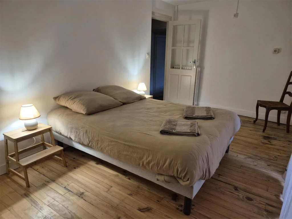 Chambre chaleureuse avec lit double, linge beige et lampes de chevet