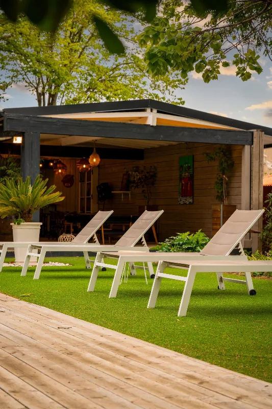 Espace détente extérieur avec chaises longues blanches sous pergola et pelouse