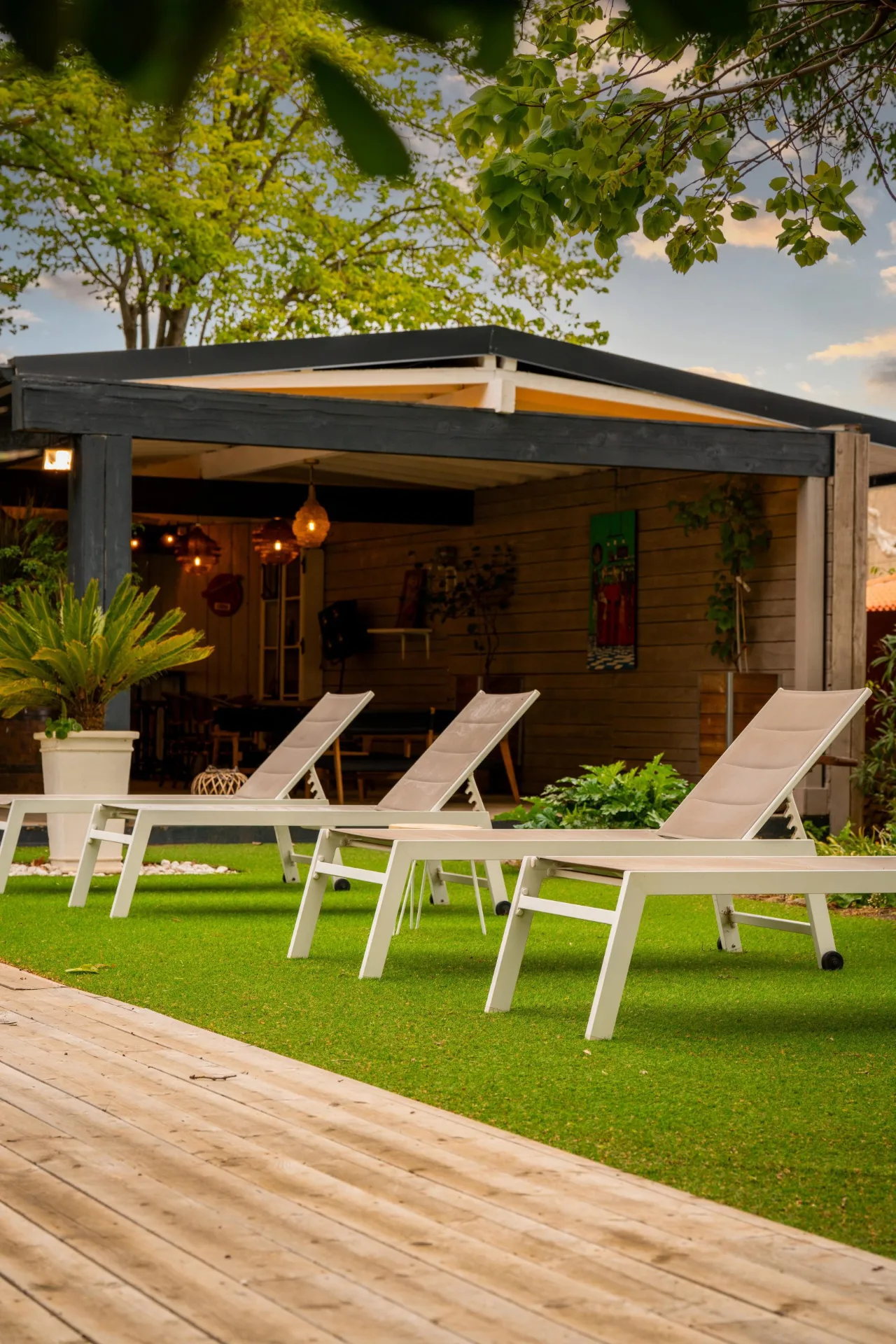 Espace détente extérieur avec chaises longues blanches sous pergola et pelouse