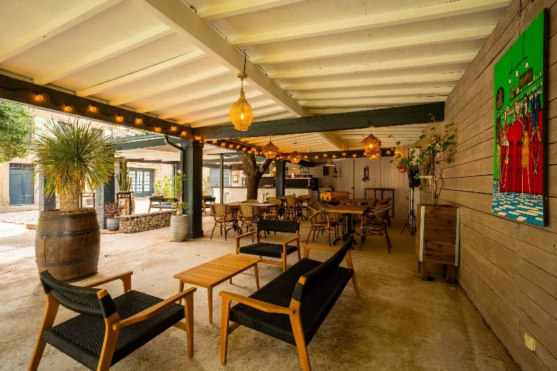 Terrasse couverte avec mange-debout, guirlandes lumineuses et mobilier coloré