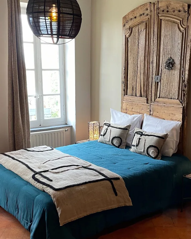 Chambre aux tons bleus avec armoire ancienne en bois et tête de lit capitonnée