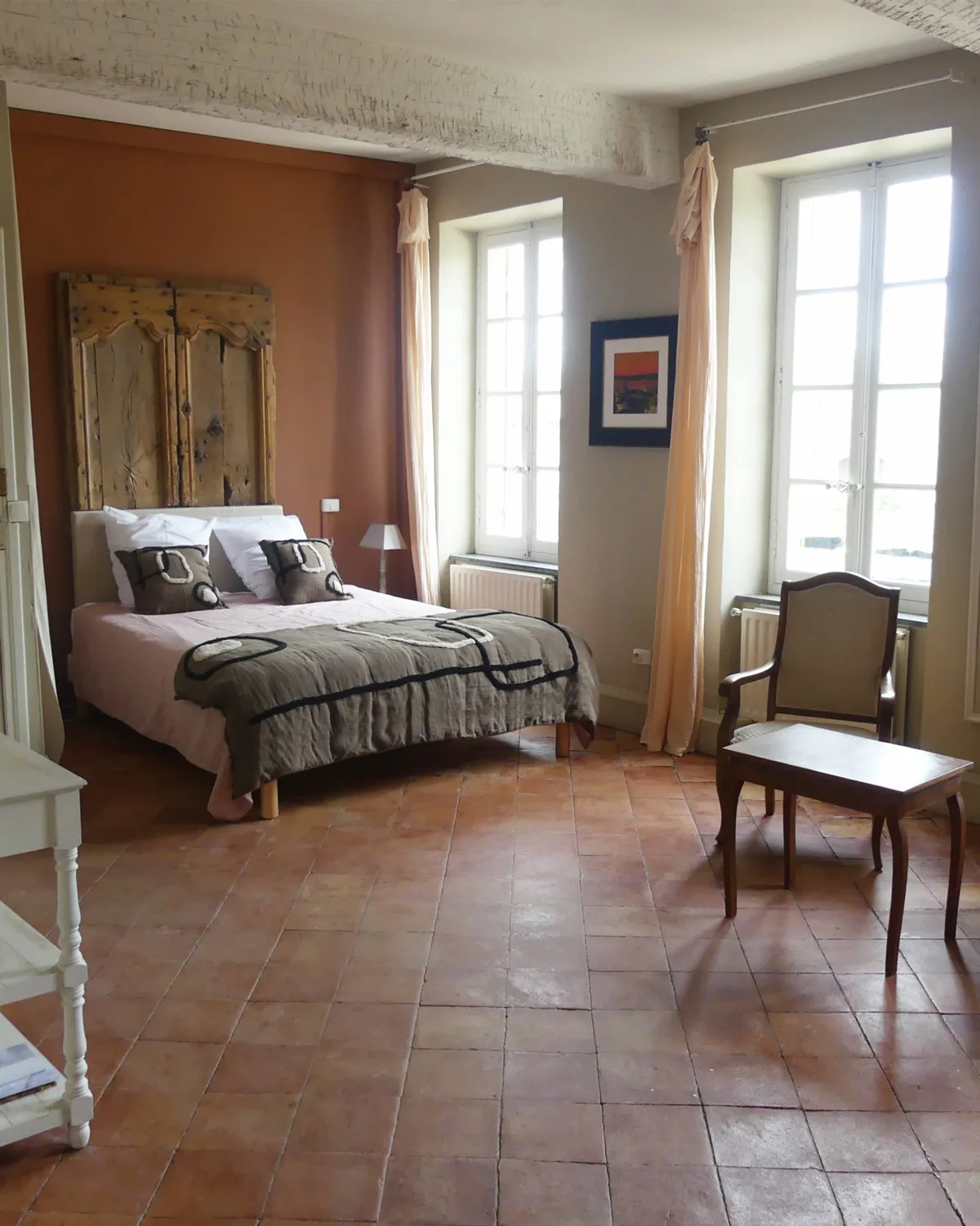 Chambre aux teintes roses façon boudoir avec fauteuil et lit en fer forgé
