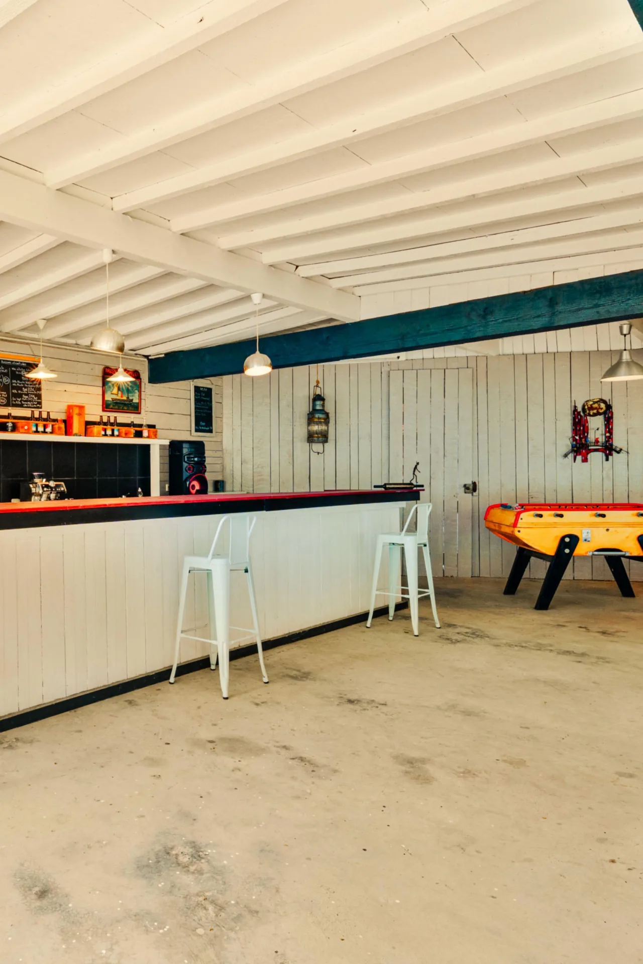 Espace bar convivial avec baby-foot sous une charpente en bois clair