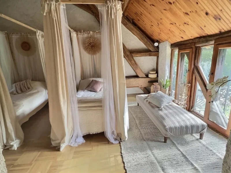 Chambre romantique avec lit à baldaquin voilé sous charpente en bois