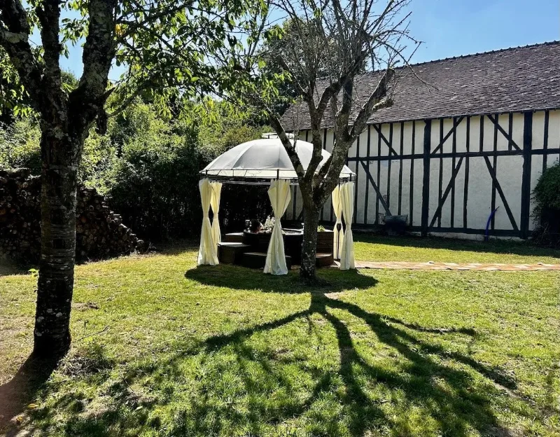 Rotonde en bois abritant le jacuzzi entourée d'arbres dans le jardin