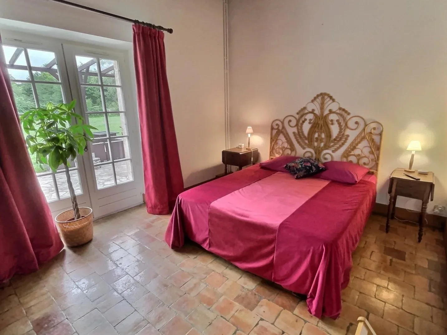Chambre aux tons framboise avec tête de lit capitonnée et rideaux rouges