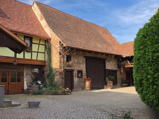 Façade en pans de bois et toit à forte pente de l'ancienne bâtisse viticole du XVIIIe siècle