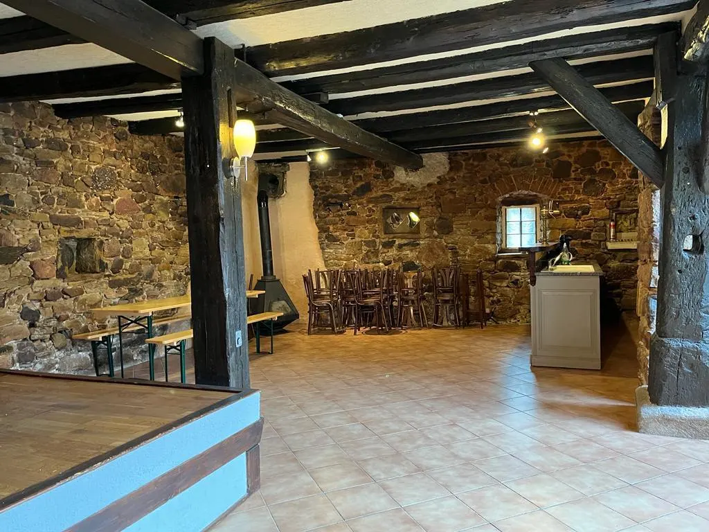 Caveau voûté en pierre avec cheminée traditionnelle, tables et bancs pour les réceptions