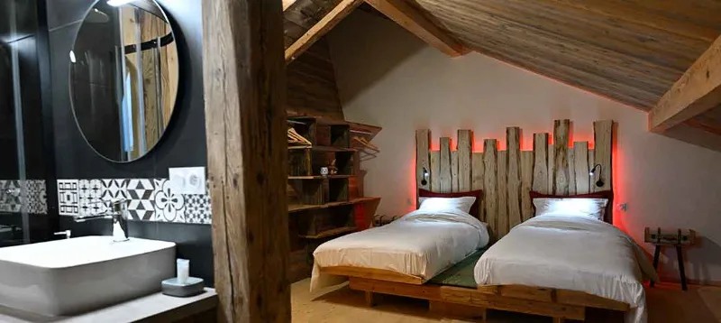 Chambre avec deux lits jumeaux et tête de lit en bois éclairée