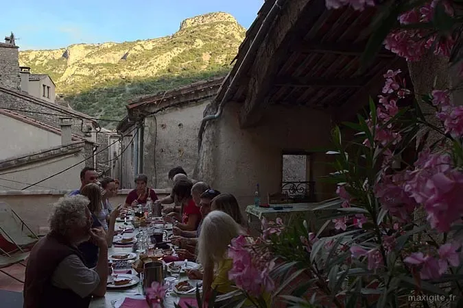 Repas de groupe en terrasse avec vue sur falaises calcaires au coucher du soleil