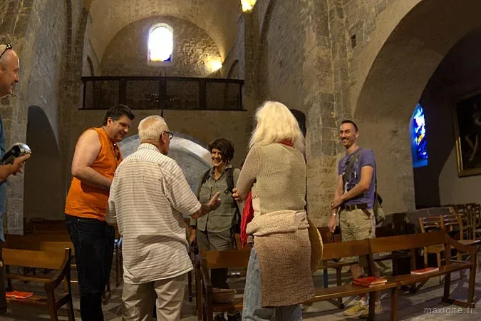 Groupe de visiteurs en visite dans une église romane en pierre