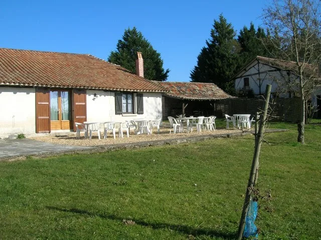 Grande terrasse extérieure aménagée avec tables et chaises pour les repas de groupe