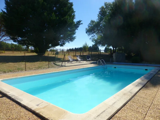 Piscine privée avec plage en dalles, transats et vue dégagée sur la campagne