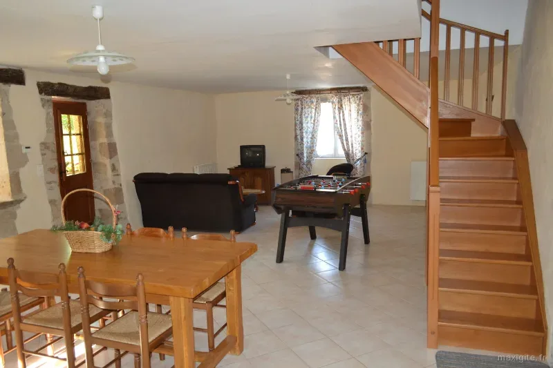 Salle de jeux avec baby-foot, canapé et escalier en bois menant à l'étage