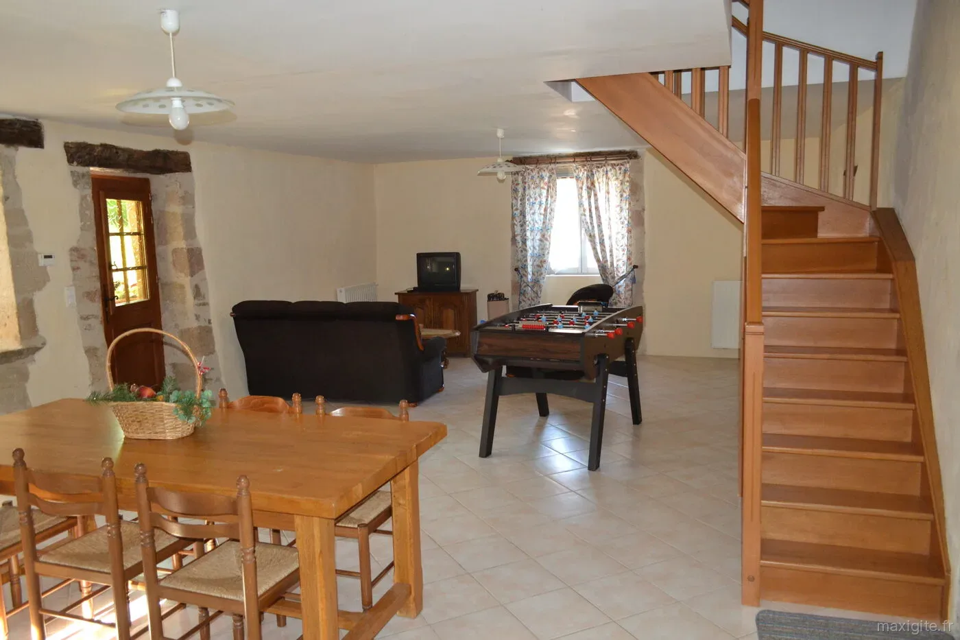 Salle de jeux avec baby-foot, canapé et escalier en bois menant à l'étage