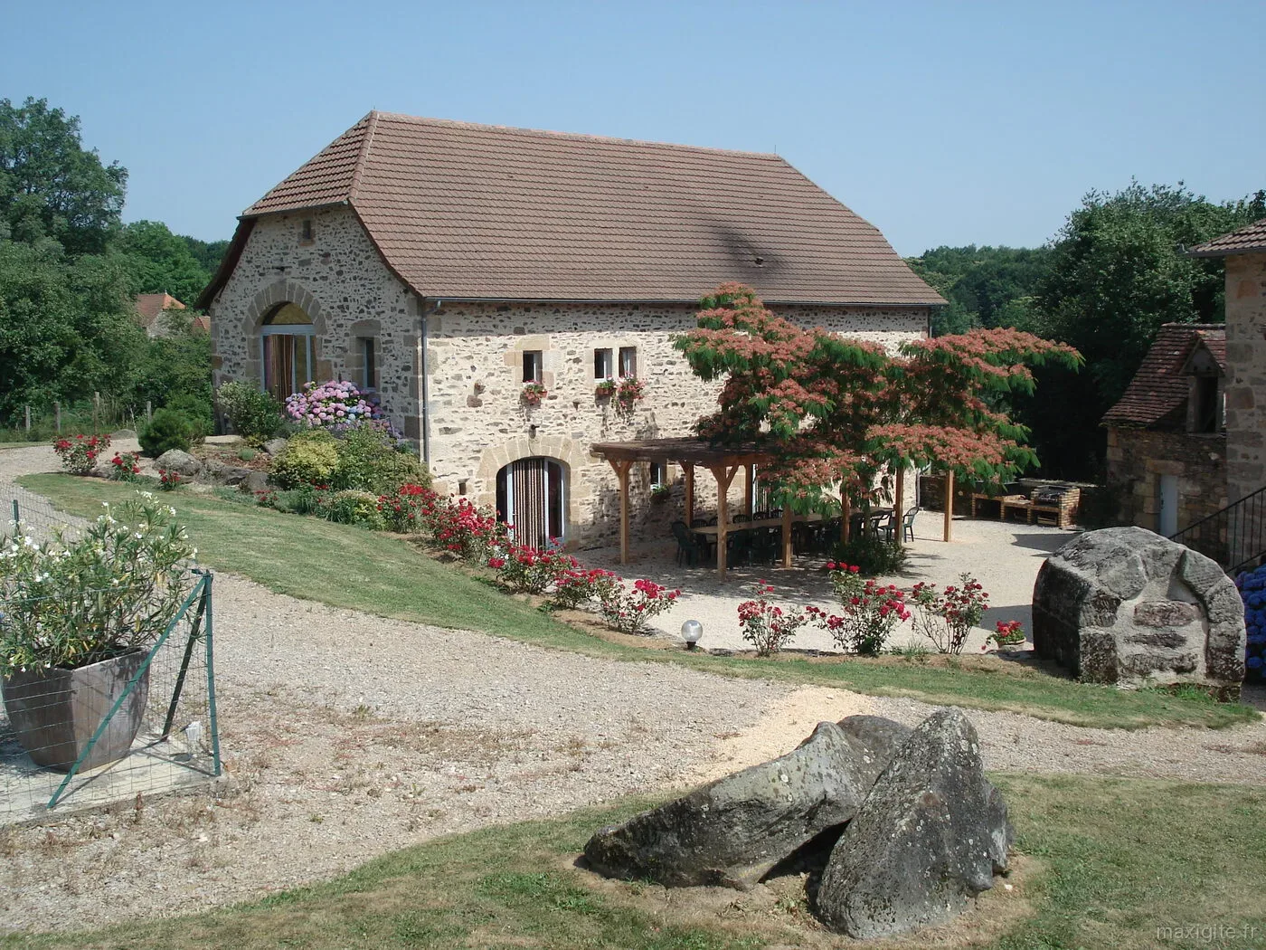 Gîte de groupe Le Pré de Fontalzines à Espeyroux — Grande bâtisse quercynoise en pierre avec pergola, terrasse et longues tablées extérieures, capacité 21 personnes