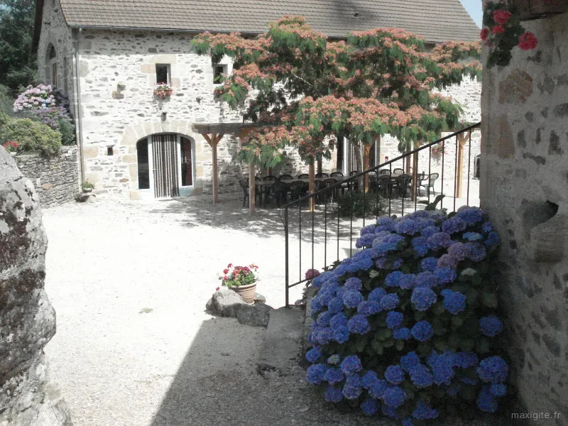 Façade principale du gîte fleurie d'hortensias avec pergola et coin repas extérieur