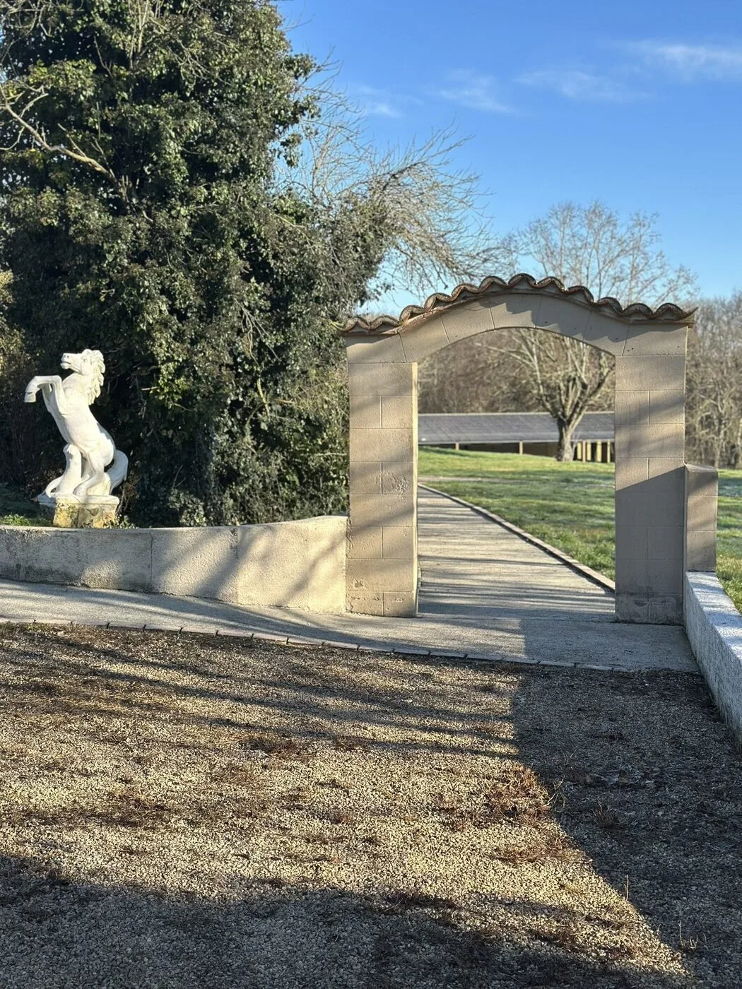 Porche en pierre voûté menant au parc, orné d'une statue de cheval