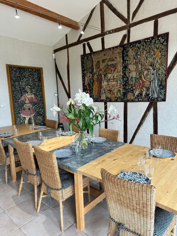 Salle à manger avec grandes tables en bois et tapisseries décoratives sur pans de bois