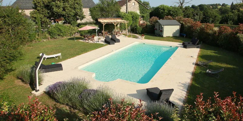 Piscine extérieure sécurisée vue du ciel, entourée de terrasse et de verdure
