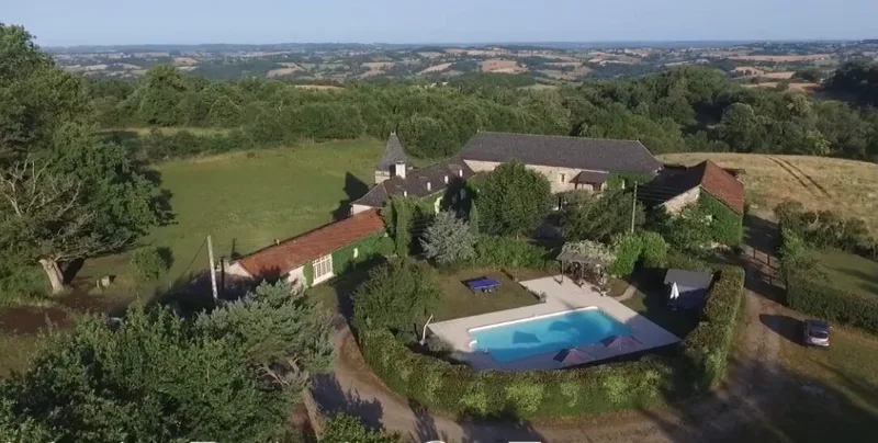 Vue aérienne du domaine avec bâtisse en pierre, grande piscine et parc arboré