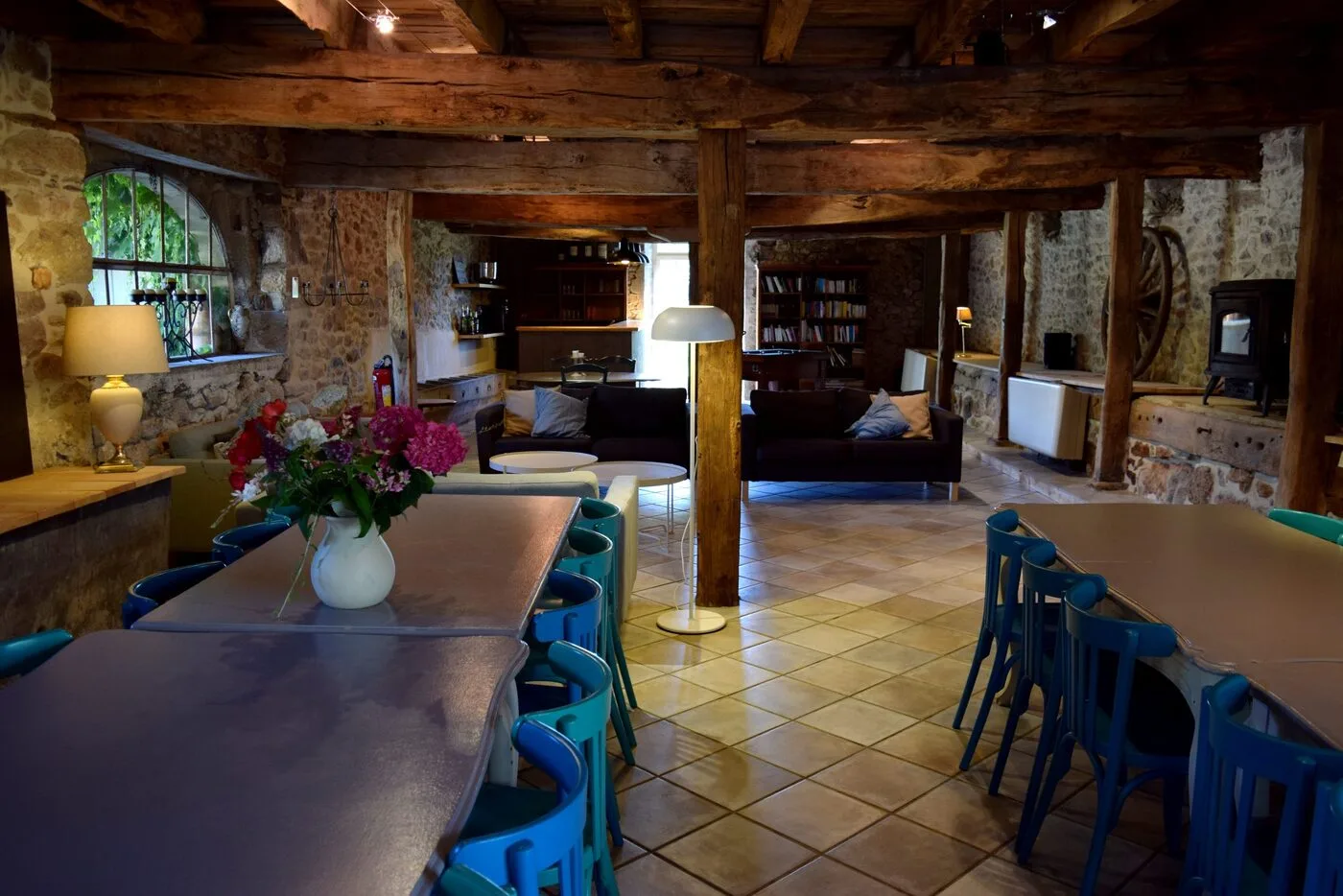 Grand séjour voûté avec poutres apparentes, canapés et longue table conviviale