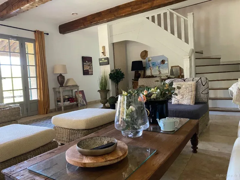 https://www.maxigite.fr/media/annonces/326/8e0b2a6b-39b1-4175-8811-c1a3ac93d174-thumb.webp/Grand salon avec poutres apparentes, canapés et escalier en bois menant à l'étage