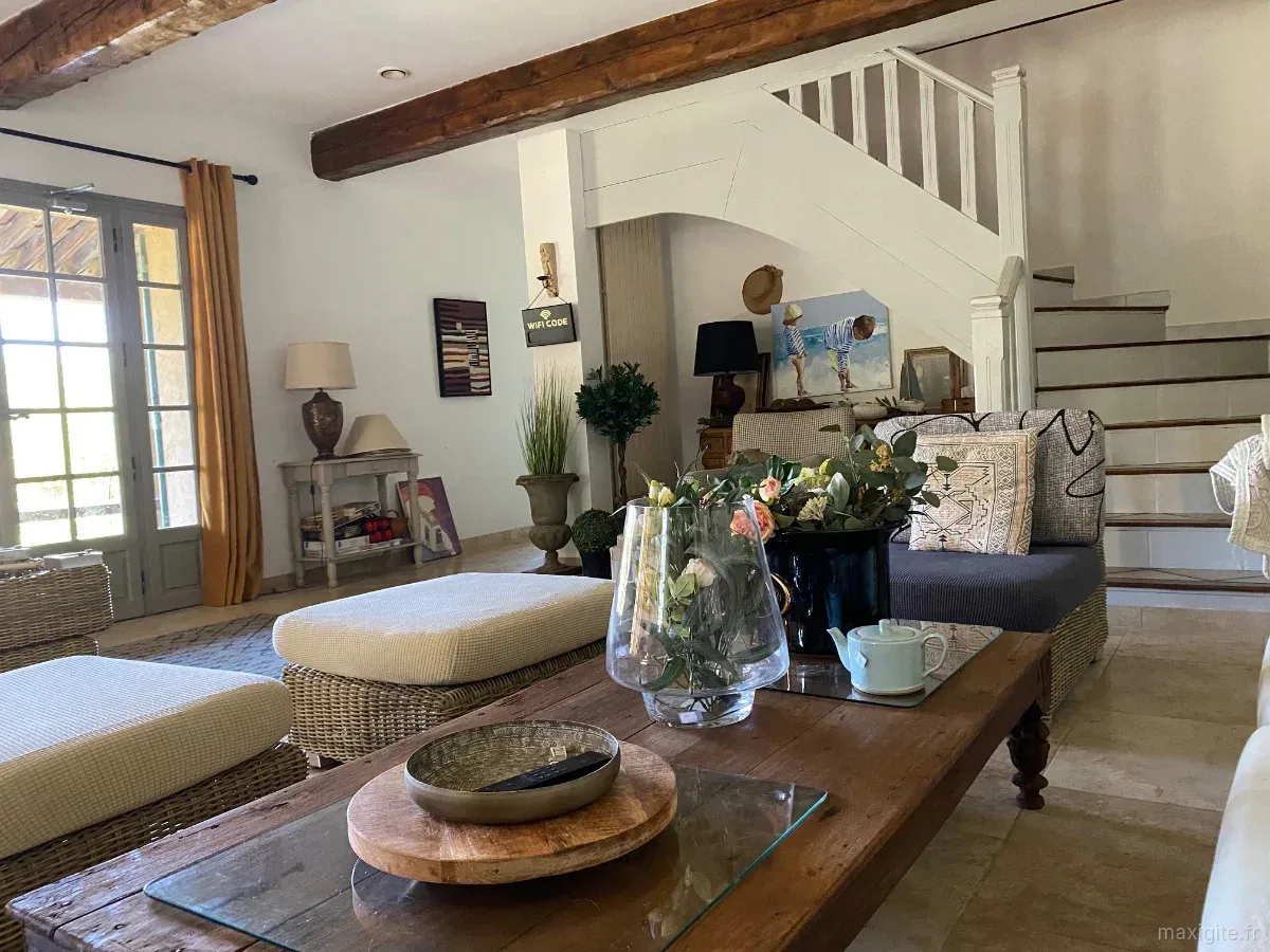 https://www.maxigite.fr/media/annonces/326/8e0b2a6b-39b1-4175-8811-c1a3ac93d174-thumb.webp/Grand salon avec poutres apparentes, canapés et escalier en bois menant à l'étage