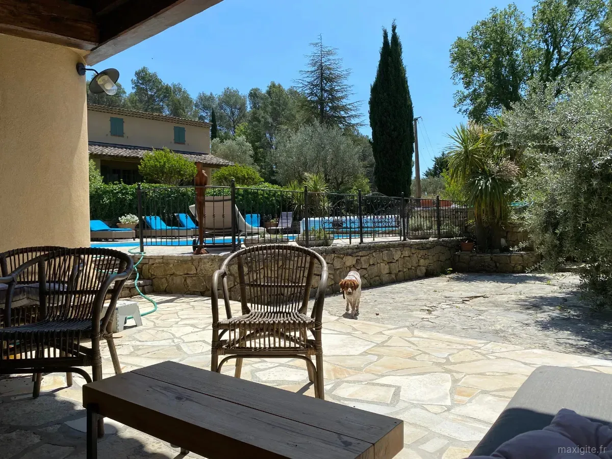 Façade et piscine vues depuis la terrasse couverte avec mobilier d'extérieur