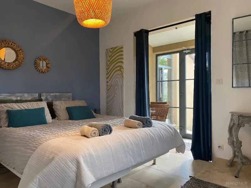 Chambre bleu cobalt avec grand lit, tête de lit en bois et accès direct au jardin
