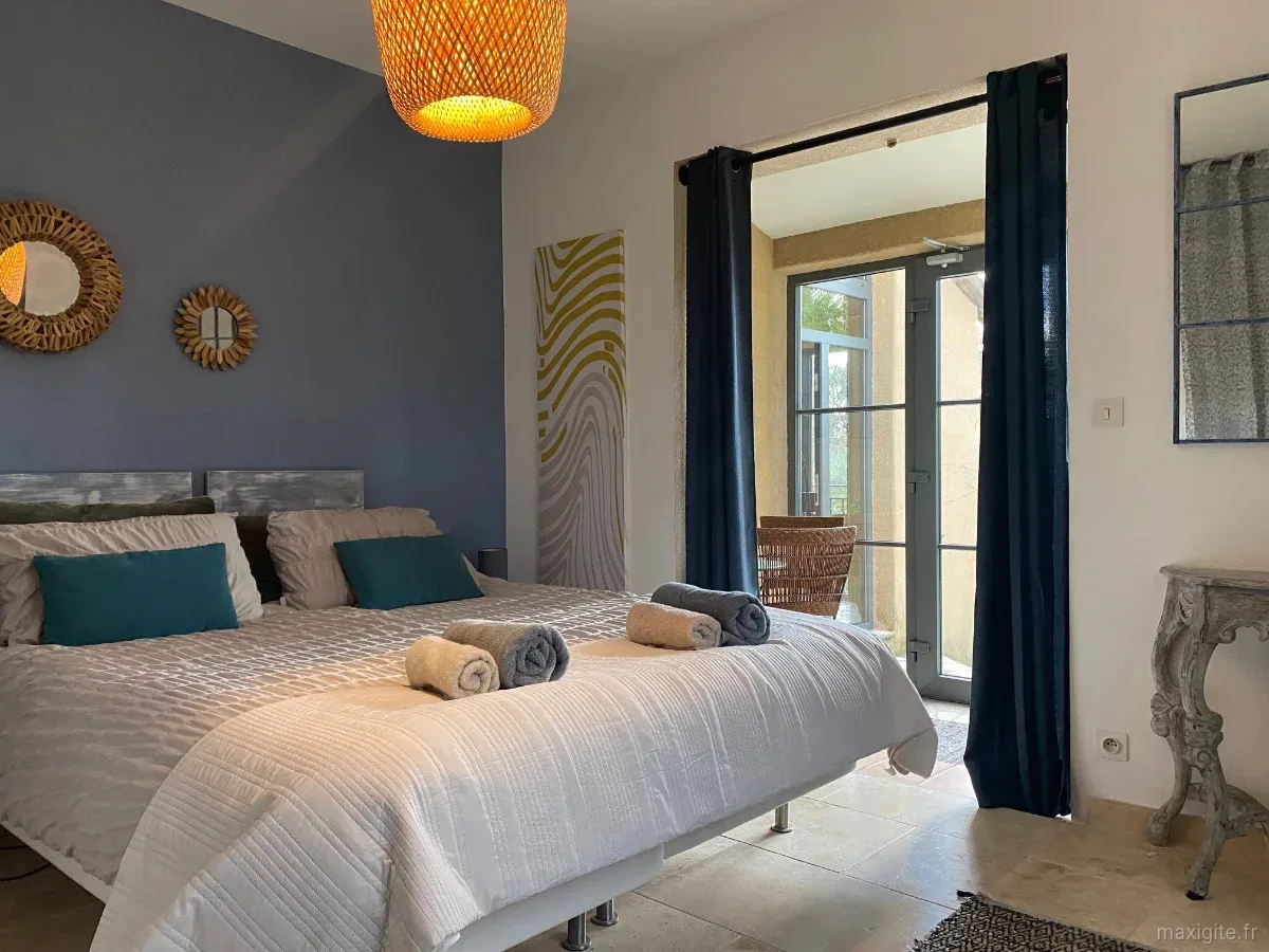 Chambre bleu cobalt avec grand lit, tête de lit en bois et accès direct au jardin