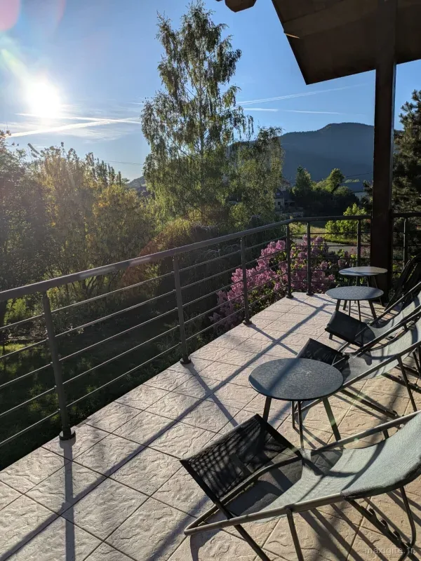 Terrasse panoramique avec tables et chaises, vue dégagée sur la vallée du Vercors au soleil