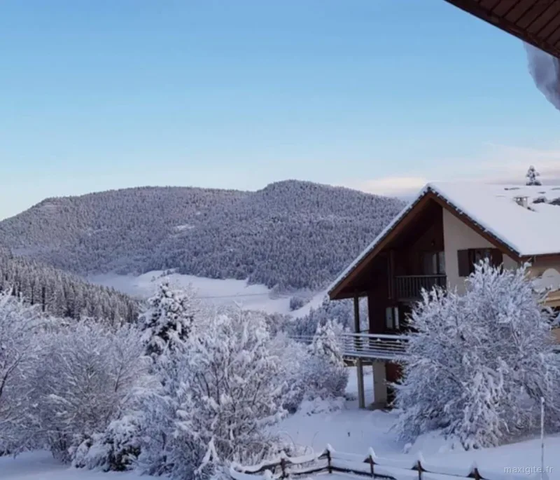 Chalet enneigé en hiver au coucher du soleil, face aux montagnes du Vercors sous la neige