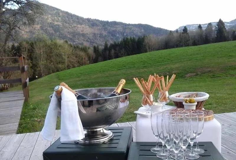 Terrasse extérieure avec seau à champagne et flûtes, vue panoramique sur les montagnes environnantes
